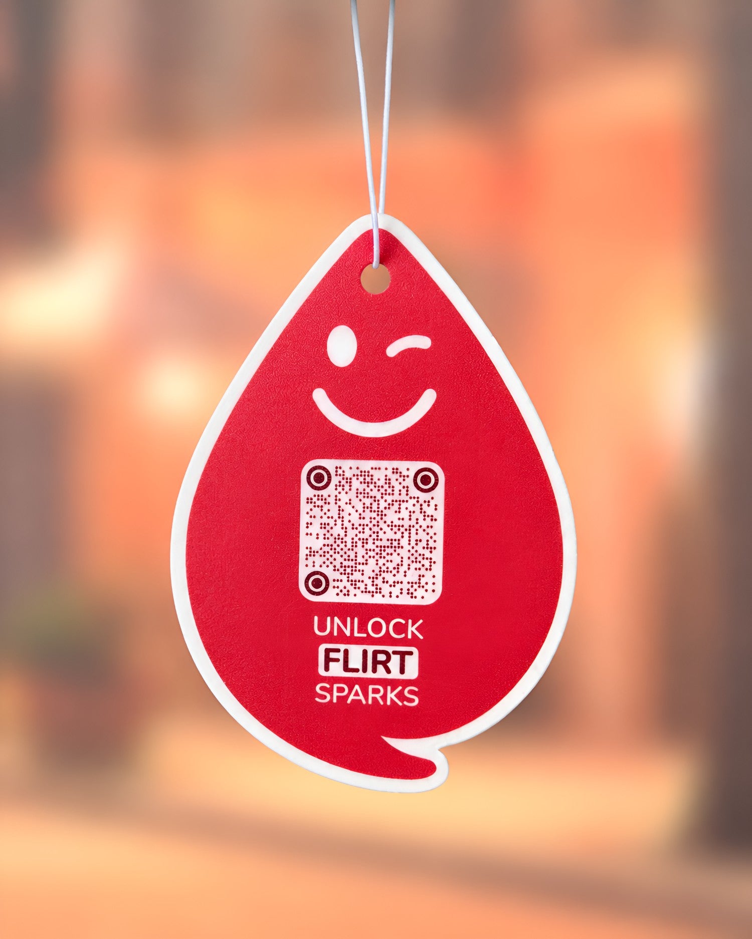 Spark FLIRT Duftanhänger mit QR-Code von ScanTheDrop vor warmem Hintergrund